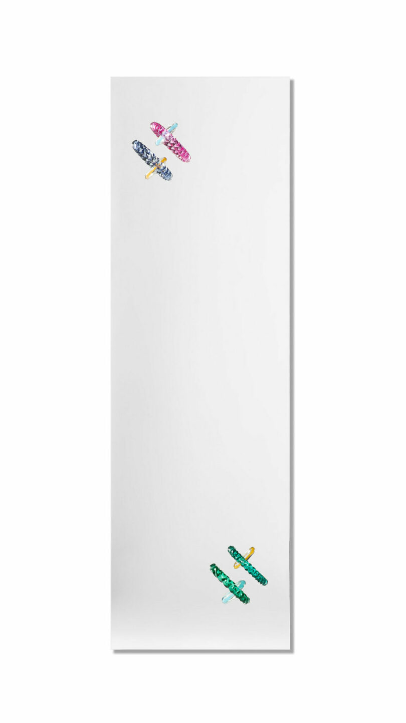 A white rectangular yoga mat with illustrations of three colorful seaplanes—pink, blue, and green—scattered across the surface.