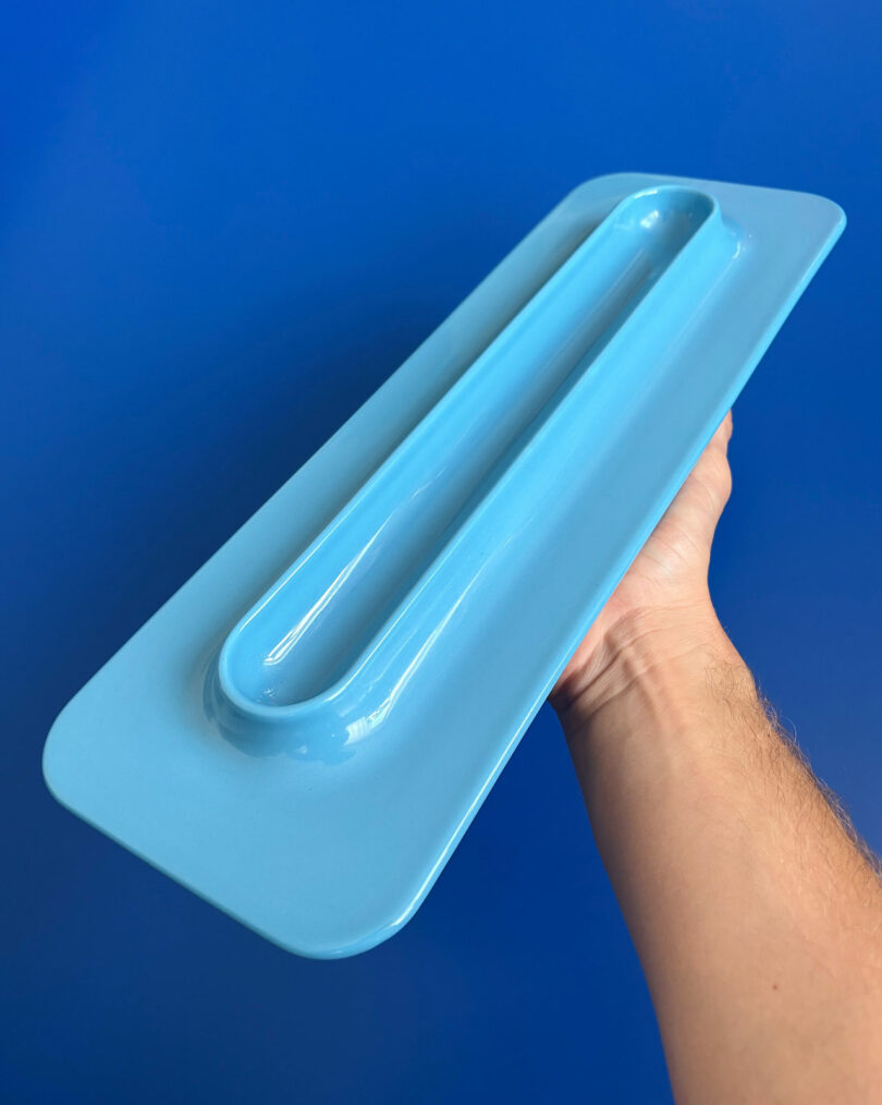 The person keeps the blue rectangular plastic object with a raised lever made of solid blue background.