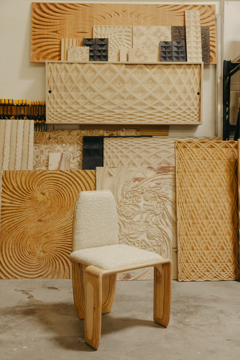 Einige große, komplexe geschnitzte Holzpaneele, die sich an den Wänden lehnen, befinden sich ein strukturierter Holzstuhl, der an den mutigen Stil von Kelly Wearstler erinnert.