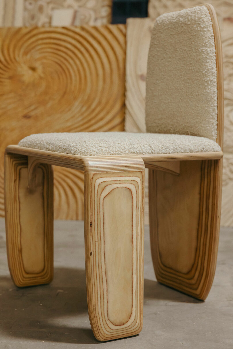 Moderne Stühle mit gebogenen, laminierten Holzbeinen und cremefarbenen gepolsterten Sitz und Rückenlehne, inspiriert von Kelly Wearstler, gebaut vor dem Hintergrund unvollendeter Holzpaneele.