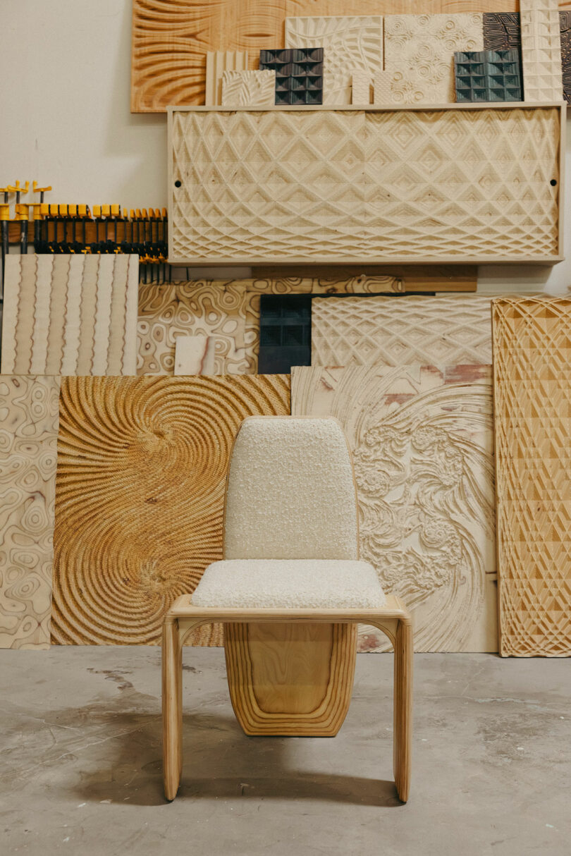 Moderne Holzstühle mit leuchtend gepolstertem Sitz und Rückenlehne sitzen vor den Wänden, die mit komplexen geschnitzten Holzpaneelen dekoriert sind und einen kühnen, künstlerischen Geist der ikonischen Designs von Kelly Wearstler verursachen.