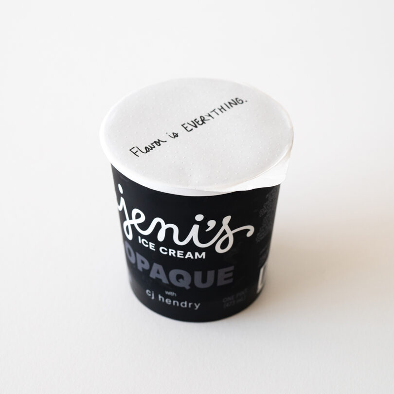 A black pint container of Jeni's Ice Cream labeled "OPAQUE" with "Flavor is EVERYTHING." handwritten on the white lid, placed on a white surface.