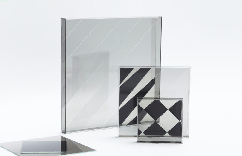 Four pieces of clear and patterned glass or acrylic stand upright on a white surface, displaying diagonal and geometric black stripes and shapes