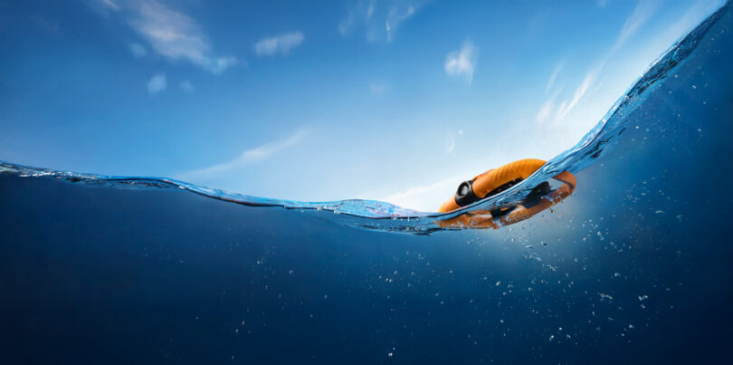 The life hole floats on the surface of peaceful blue water under clear sky.
