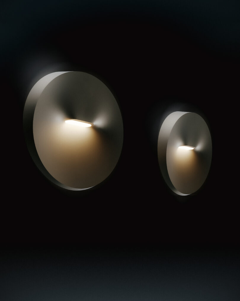 Two circular wall lights emit a soft, warm glow against a dark background