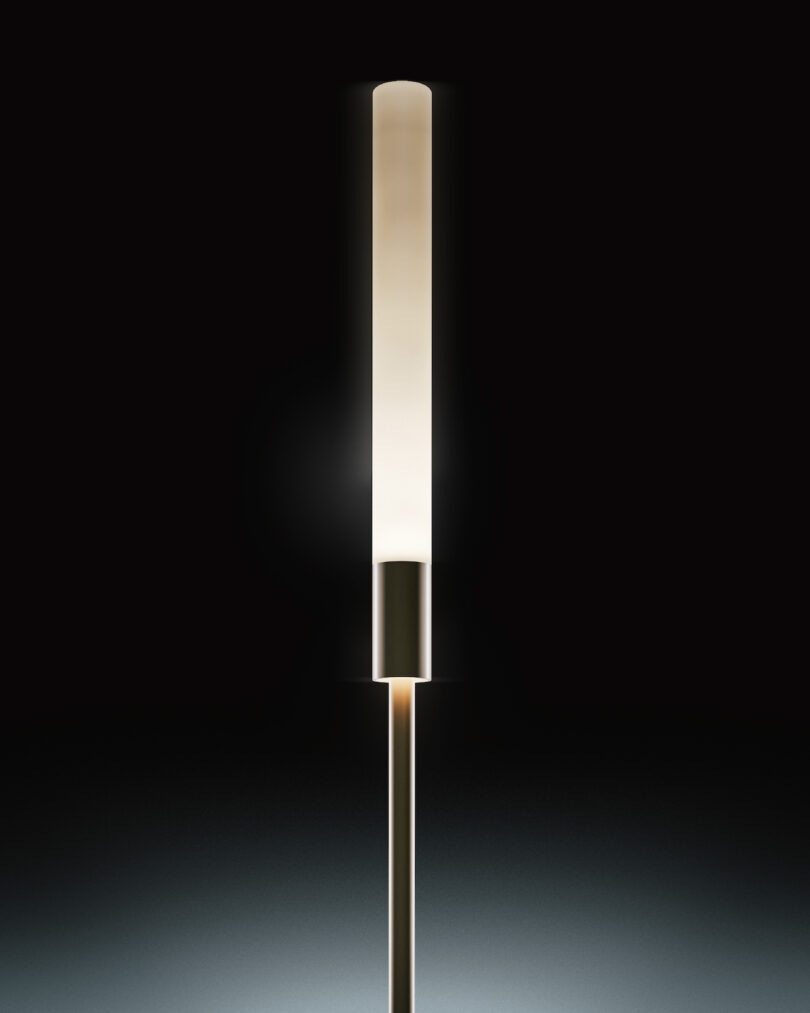 A modern, cylindrical outdoor light with a frosted glass shade emits a soft light against a dark background