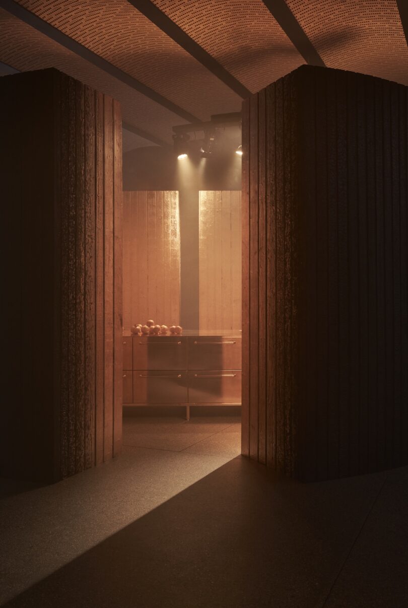 A dimly lit room with wooden panel walls, a cabinet topped with several apples, and light streaming in from above.