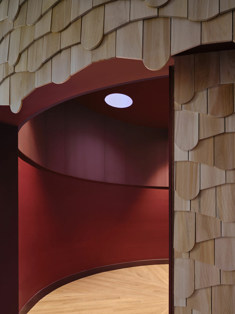 The curved inner wall in the deep red with a circular roof window, next to the wall covered, light wood for wood on the ceiling and input.