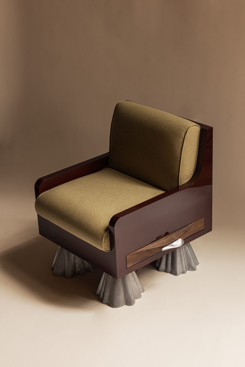 A modern armchair with olive green cushions, a glossy wooden frame, and unique gray sculpted legs, set against a neutral background.