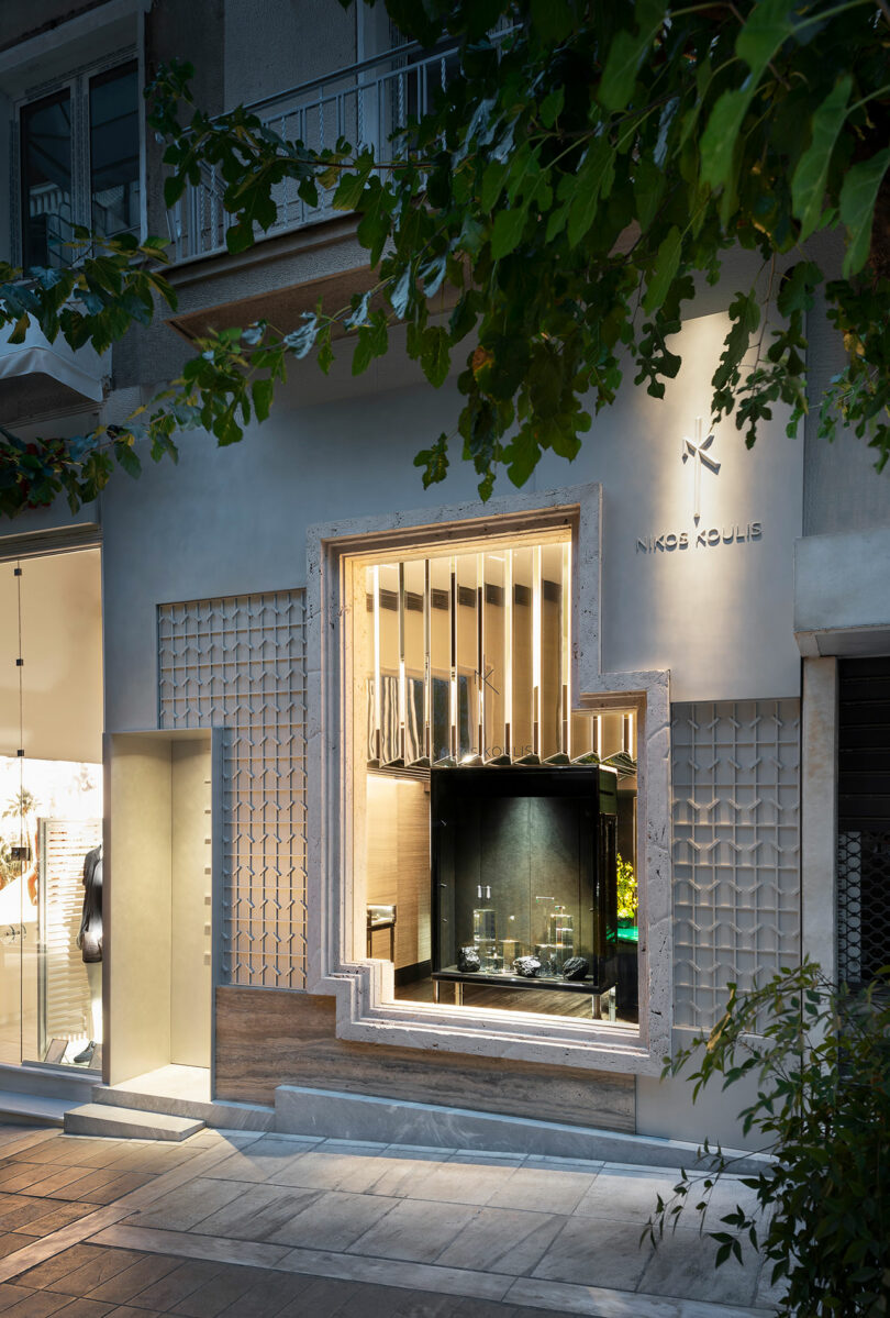 Street view of the Nikos Koulis jewelry store with a geometric, illuminated window display and a modern exterior facade.