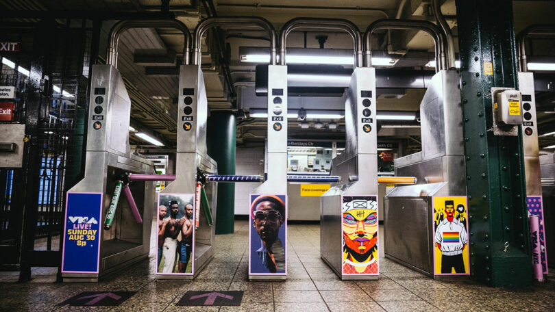 Turnstiles in a subway station are decorated with colorful posters featuring portraits and graphic art.