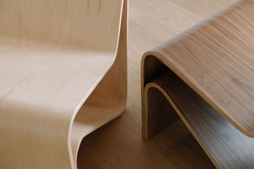 Curved plywood chair and matching table with a natural wood finish, showing smooth, modern lines on a light wooden floor.
