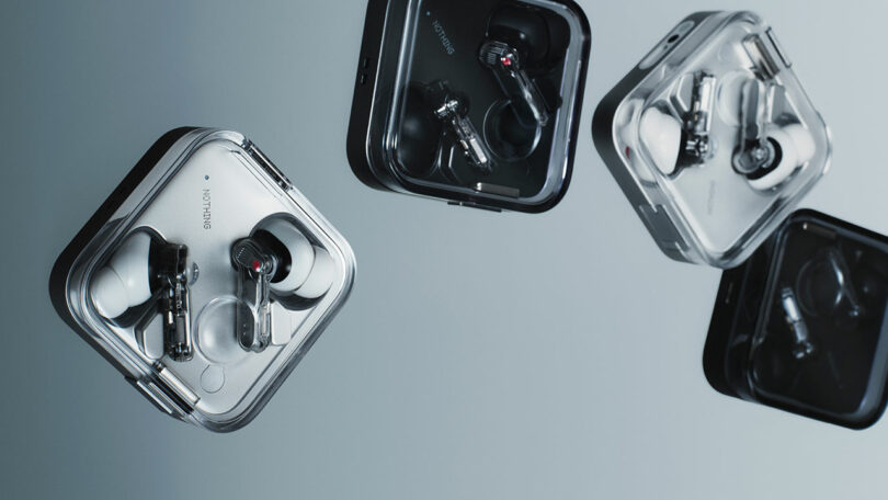 Cuatro pares de tapones para los oídos inalámbricos en una caja cuadrada transparente, que se muestran desde el ángulo de la superficie reflectante.