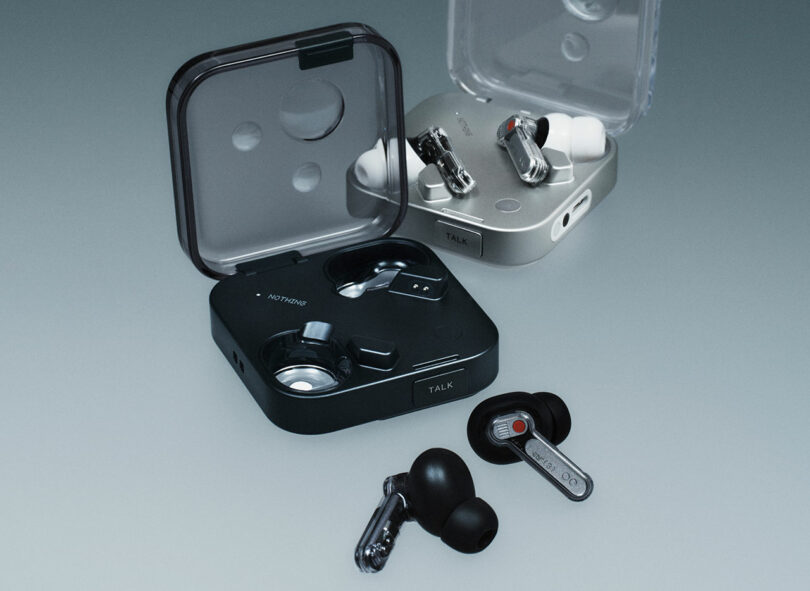 Se muestran dos pares de tapones para los oídos inalámbricos en una superficie plana, una negra y otra de plata. Un tapón para los oídos para cada par se coloca fuera de sus respectivas situaciones.