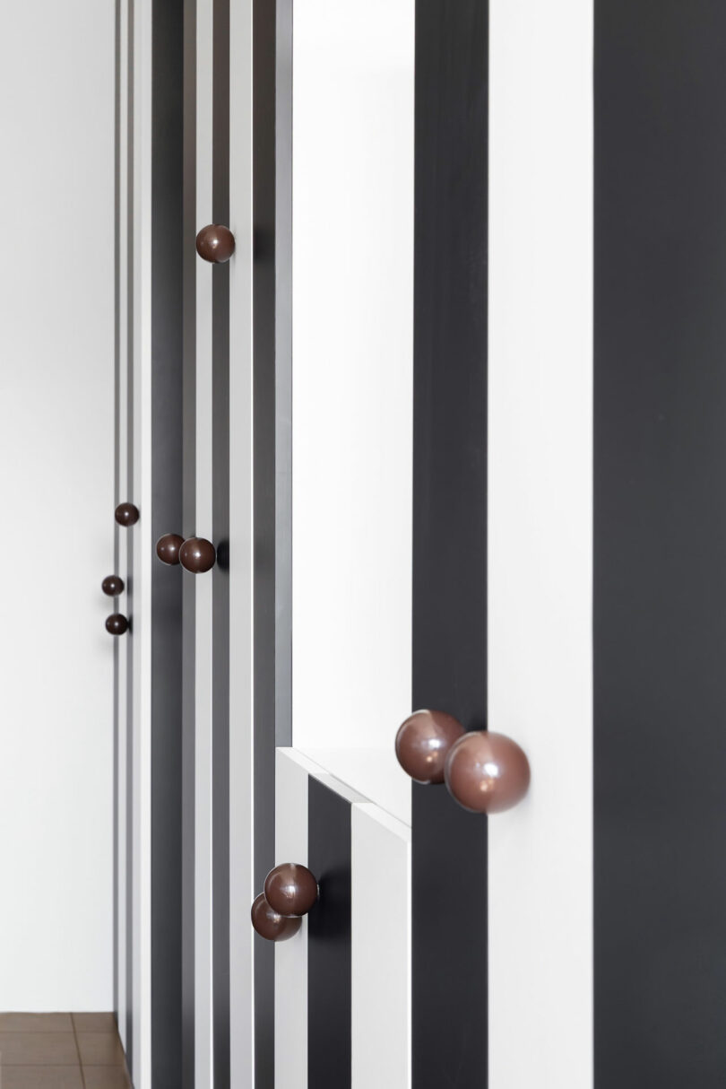 Vertical black and white striped walls with round brown knobs protruding at various heights and locations.