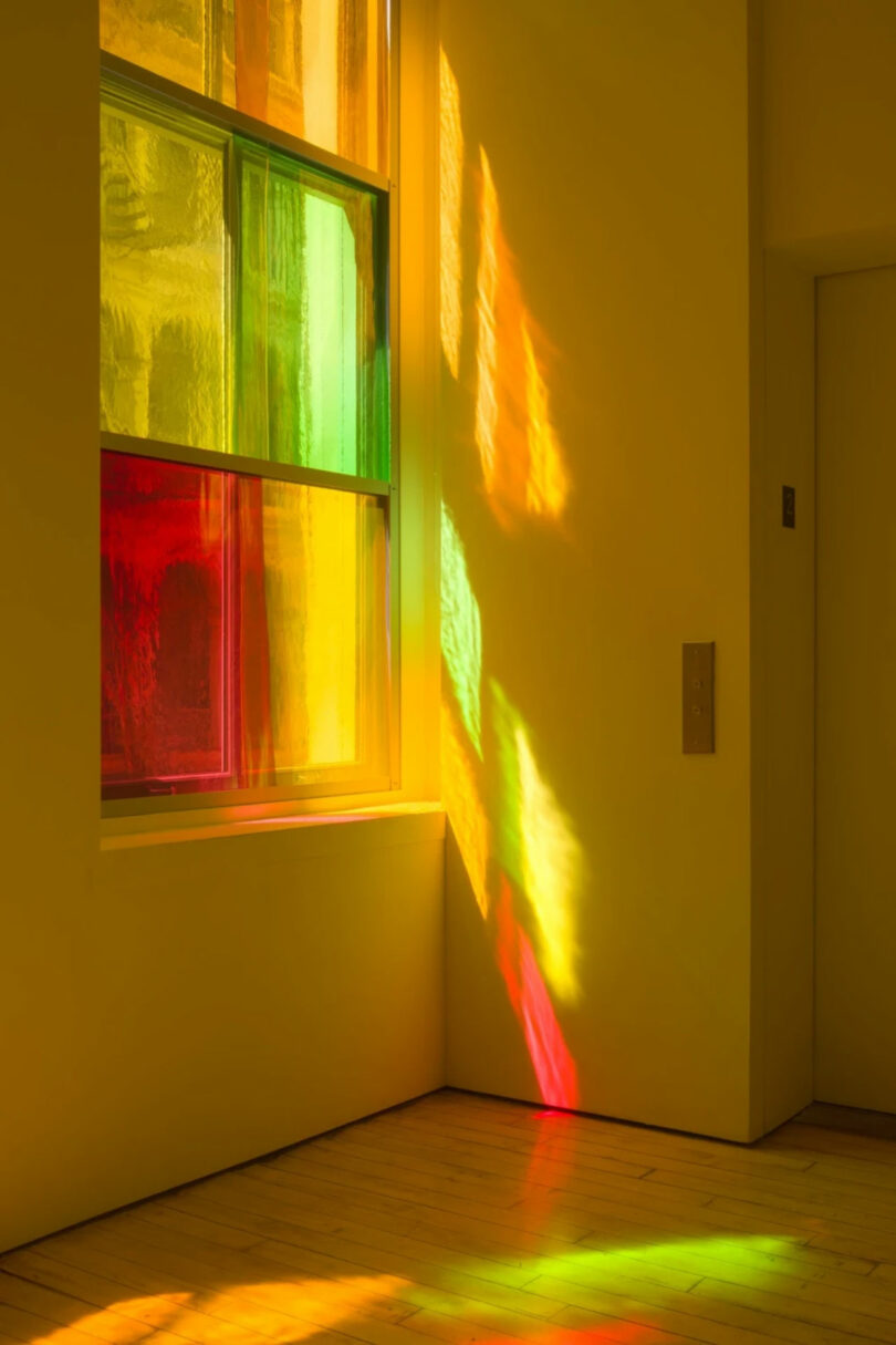 colored light filters through stained glass onto wall