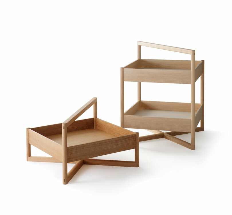 Two minimalist wooden trays, one single-level and one double-level, each with a handle and cross-shaped base, are displayed on a white background.