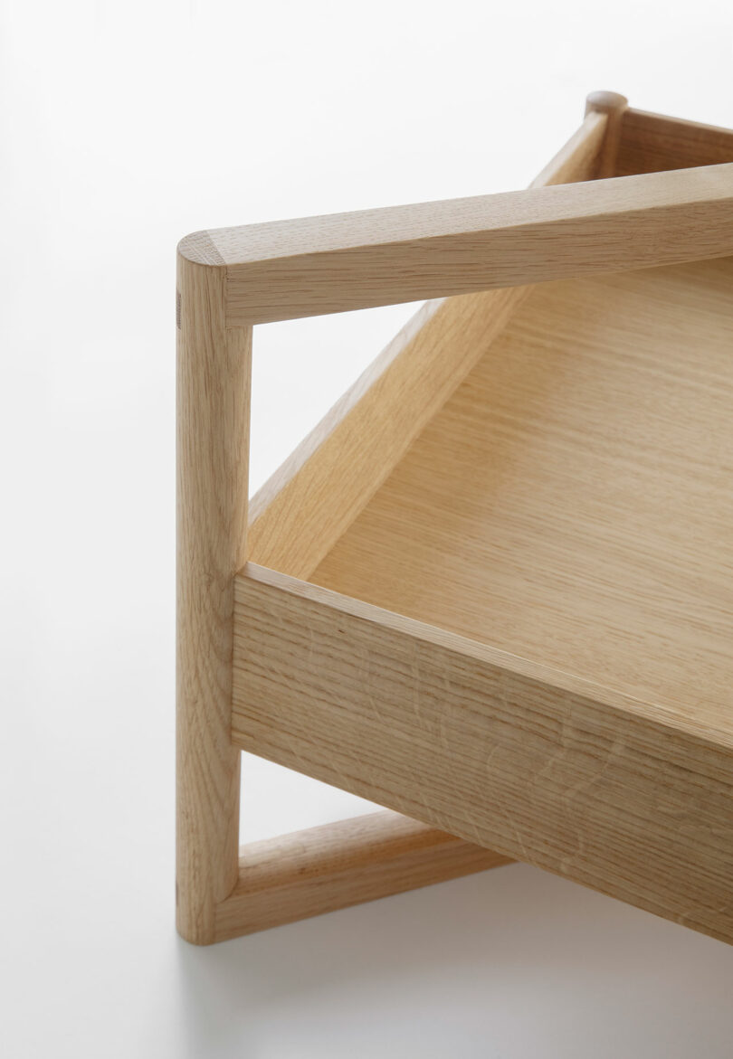 Close-up of a light wood tray with raised edges and rounded corner joints, showcasing simple, modern construction on a white background.