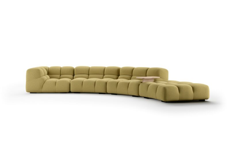 A modern, modular green sectional sofa with tufted cushions and a built-in small wood side table.