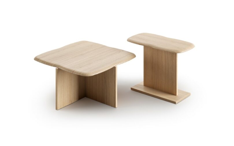 Two wooden side tables with light wood finish, each featuring a thick, rounded square or rectangular top and intersecting flat panel bases, set against a white background