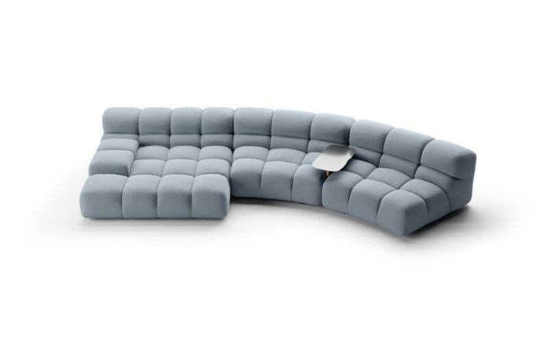 A modern, modular blue sectional sofa with tufted cushions and a built-in small wood and aluminum side table.
