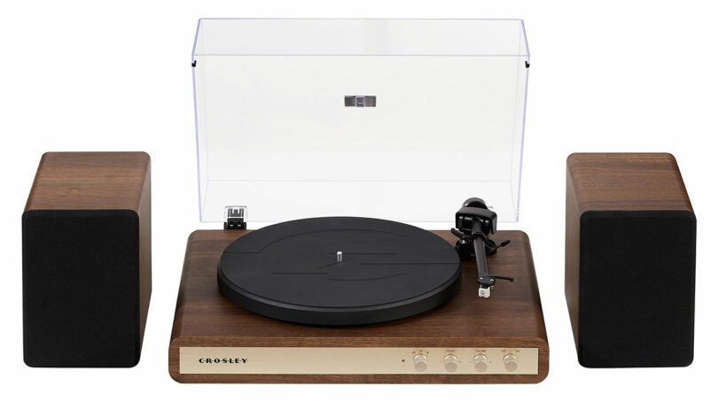 A Crosley C65 turntable with a clear dust cover, wooden base, control knobs, and two matching wooden speakers on either side.