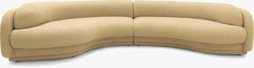 A large, curved beige sectional sofa with a textured fabric and rounded edges, shown against a plain background.