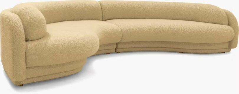 A large, curved beige sectional sofa with a textured fabric and rounded edges, shown against a plain background
