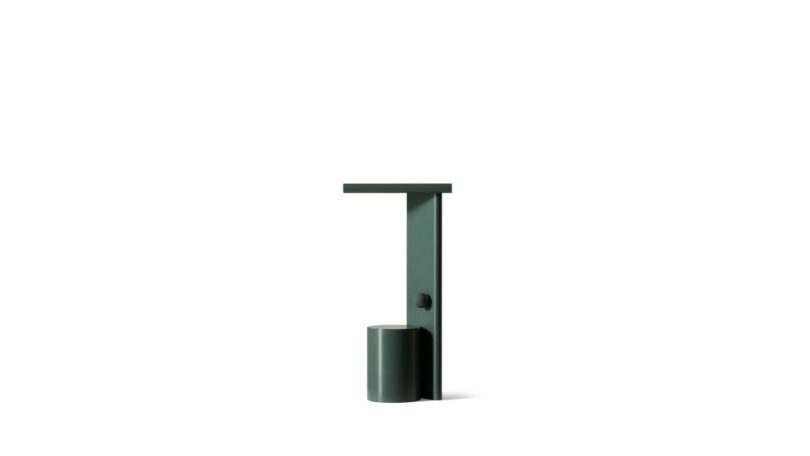 Minimalist, dark green, cylindrical table lamp with a flat top and vertical support, set against a plain white background