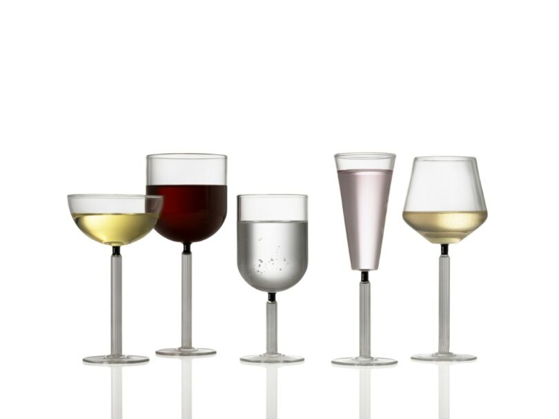 Five different types of stemmed glasses filled with various drinks, arranged in a row against a white background