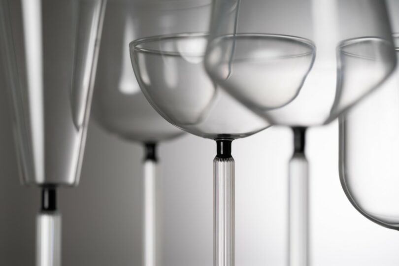 Close-up view of several empty, transparent glassware pieces, including wine glasses and cocktail glasses, arranged against a neutral background