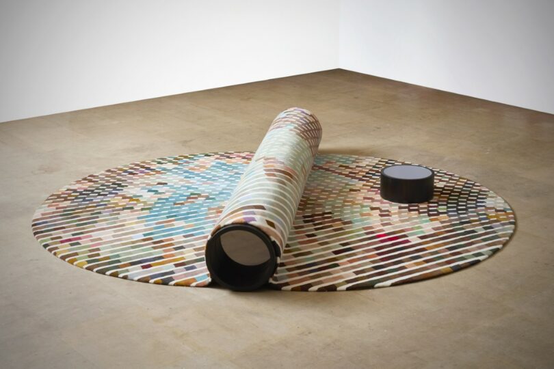 a bench-carpet hybrid, with a small round table nearby in a spacious room