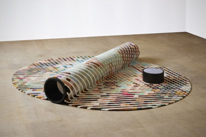 a bench-carpet hybrid, with a small round table nearby in a spacious room