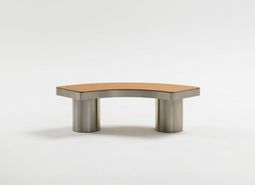 Banco curvo con base de metal y un asiento acolchado marrón en dos piernas cilíndricas