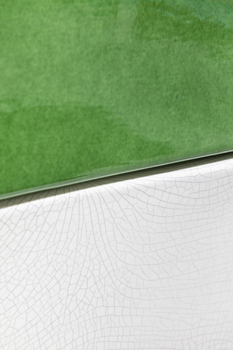 Close-up of a surface with a smooth, green upper section and a white lower section featuring a cracked, textured pattern.