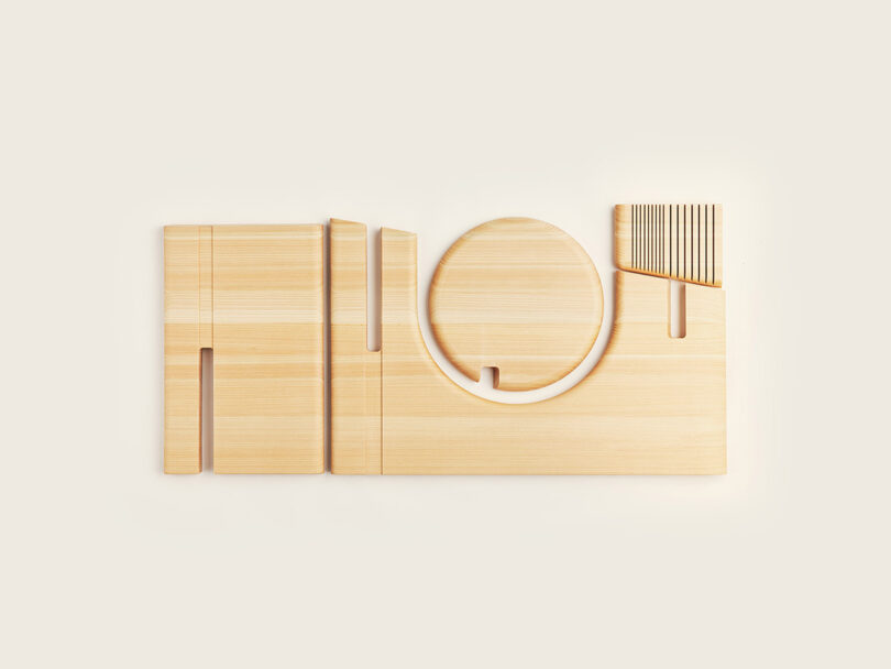 A minimalist wooden object with geometric cutouts, including a circle, rectangles, and parallel grooves, displayed on a plain light background.