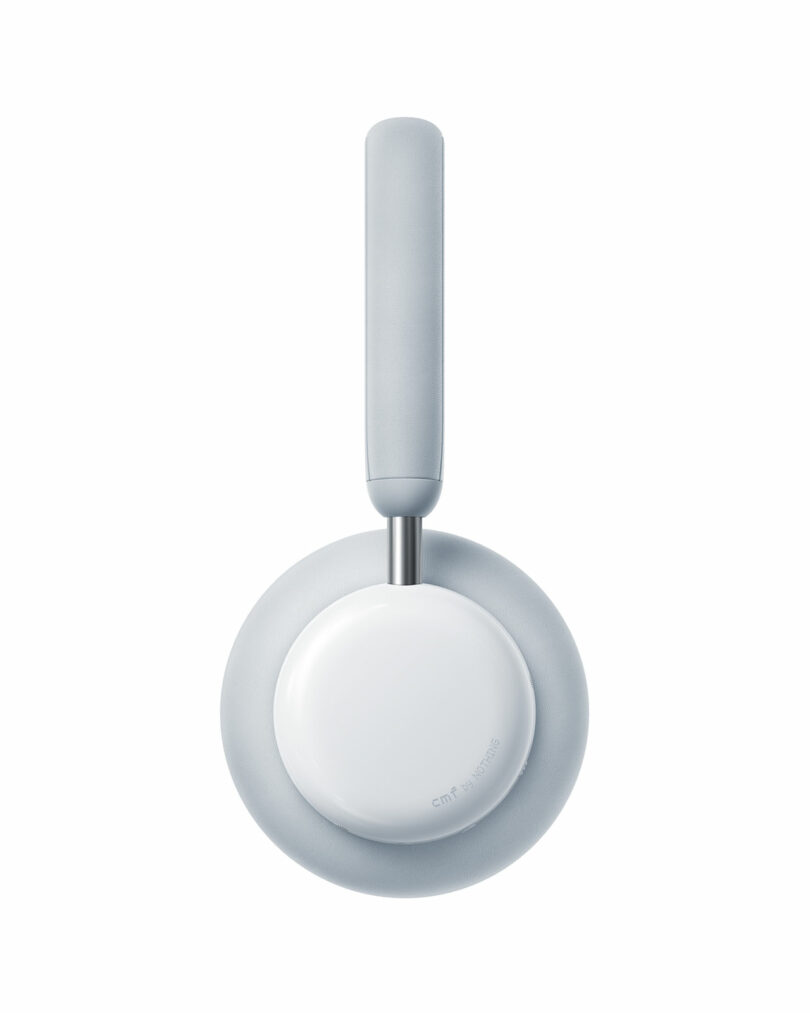 A single light gray over-ear headphone viewed from the side, showing a padded ear cup and headband against a white background.