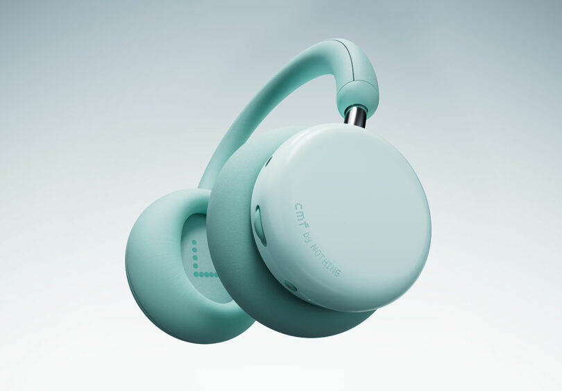 A pair of teal over-ear wireless headphones with a minimalist design, featuring the text "CMF by Nothing" on the earcup, set against a light gradient background.