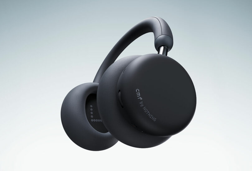 Matte black over-ear wireless headphones with padded earcups, curved headband, and "CMF by Nothing" branding on the side, shown against a gradient background.