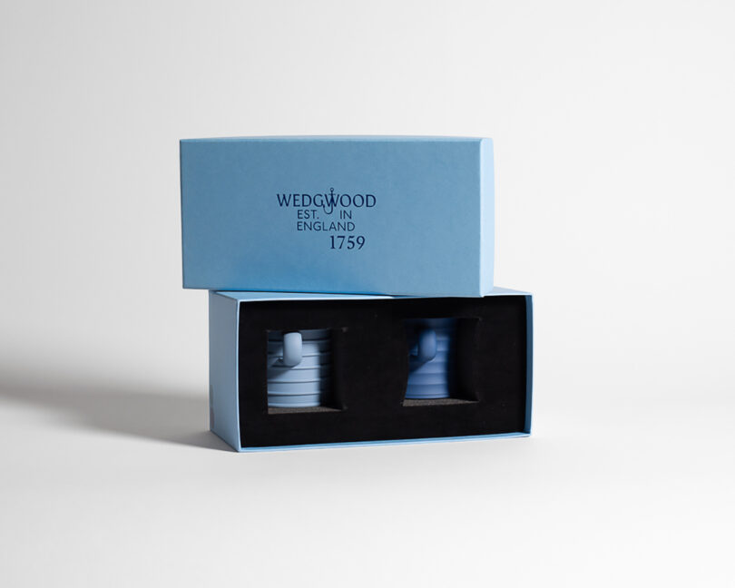 A light blue Wedgwood box with two stacked cups partially visible inside; the box lid displays "WEDGWOOD EST. IN ENGLAND 1759" in black text.