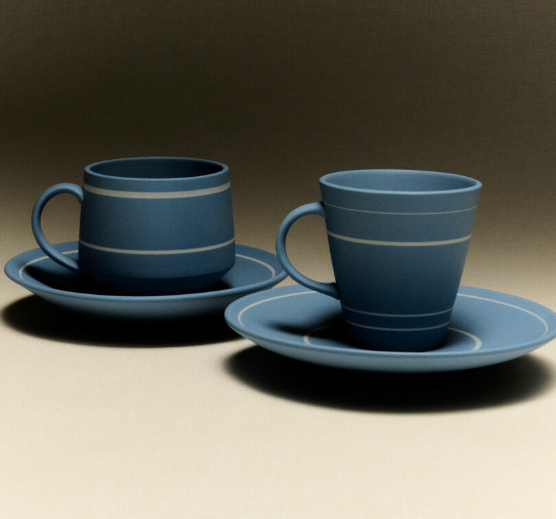 Two blue ceramic cups with matching saucers, each featuring horizontal white stripes, are placed side by side on a neutral surface, evoking the modern elegance of JW Anderson Wedgwood collaborations.
