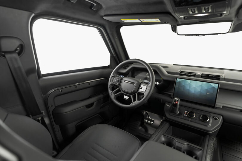 Interior view of a modern vehicle featuring a digital dashboard, touchscreen display, black seats, and a minimalist design.