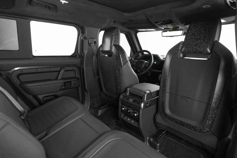 View of a car’s black leather interior from the back seat, showing front seats, rear controls, and part of the dashboard and steering wheel.
