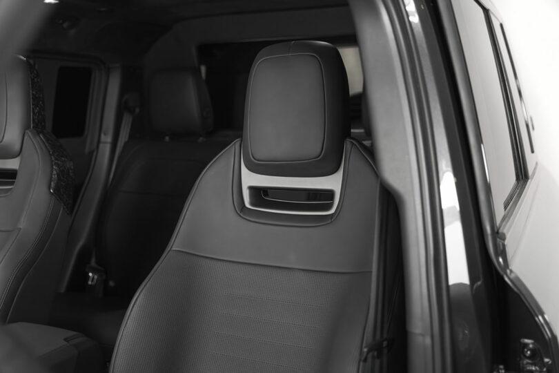 A close-up view of a modern black car seat with a headrest, located in the front row of a vehicle interior.