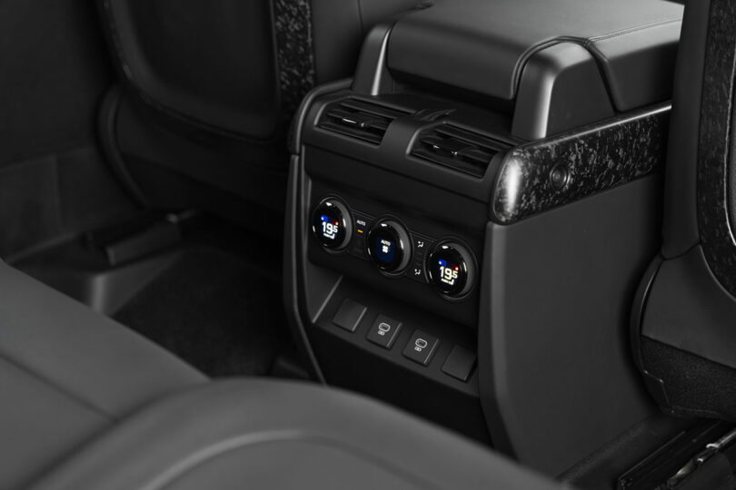 Close-up view of a car's rear seat climate control panel with digital temperature displays, air vents, and seat heating buttons.