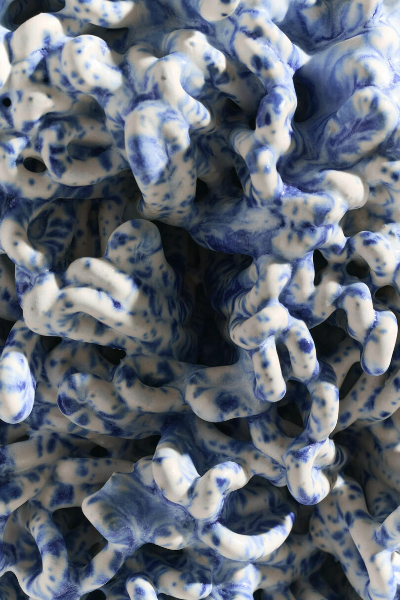 Abstract close-up of an intricate, blue and white ceramic sculpture with organic, wave-like forms and marbled patterns.