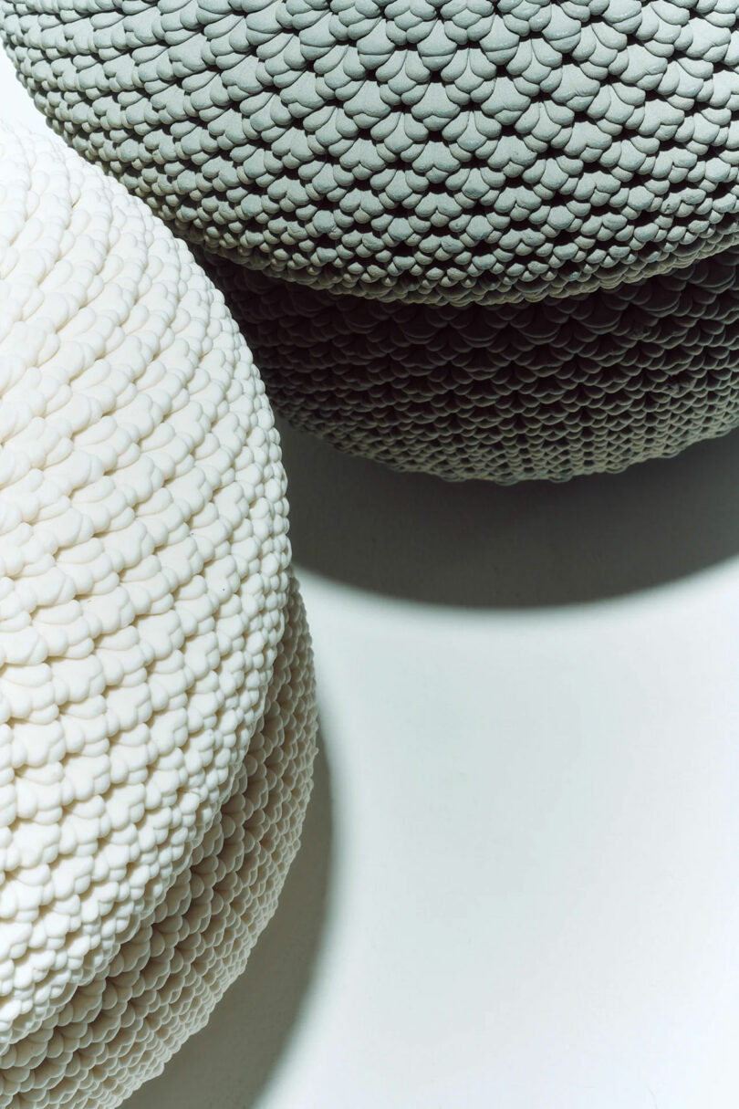 Close-up of two round, textured objects—one white and one gray—placed side by side on a flat surface, casting soft shadows.