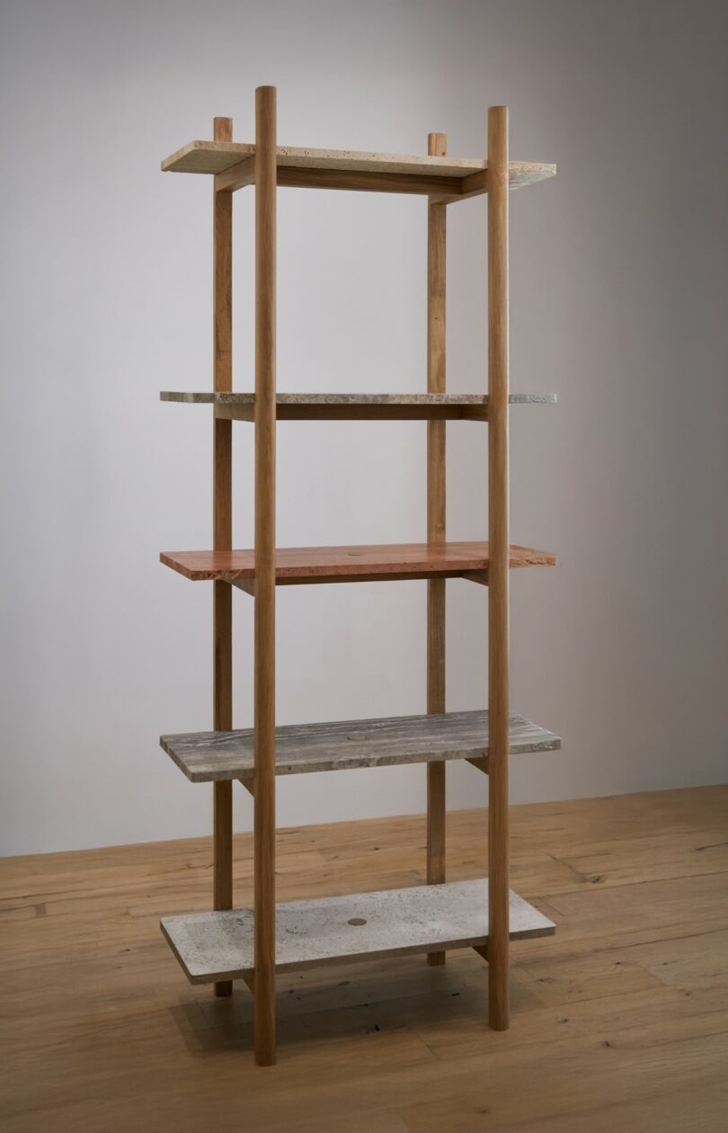 A wooden shelving unit with four upright supports and five rectangular shelves in various colors, standing on a wooden floor against a plain wall