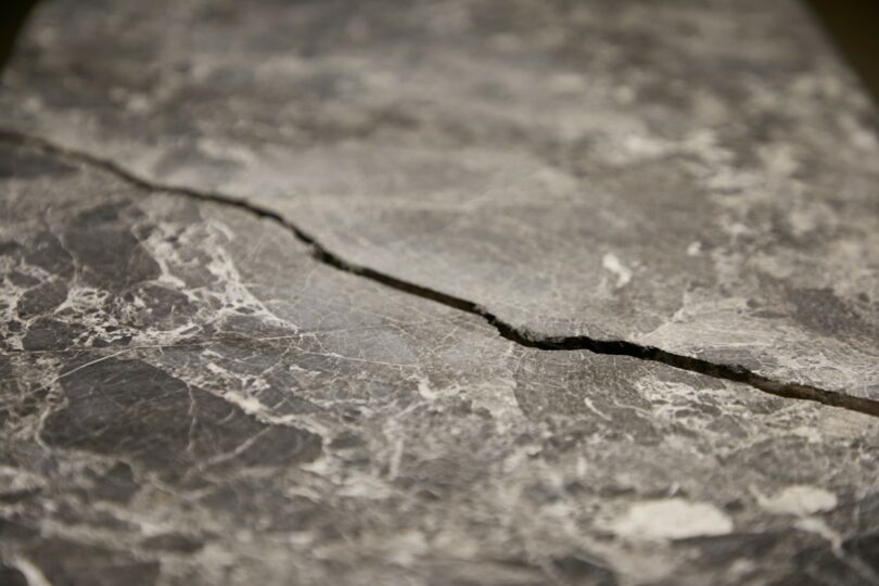 Close-up of a cracked gray stone slab with visible white veining and rough texture