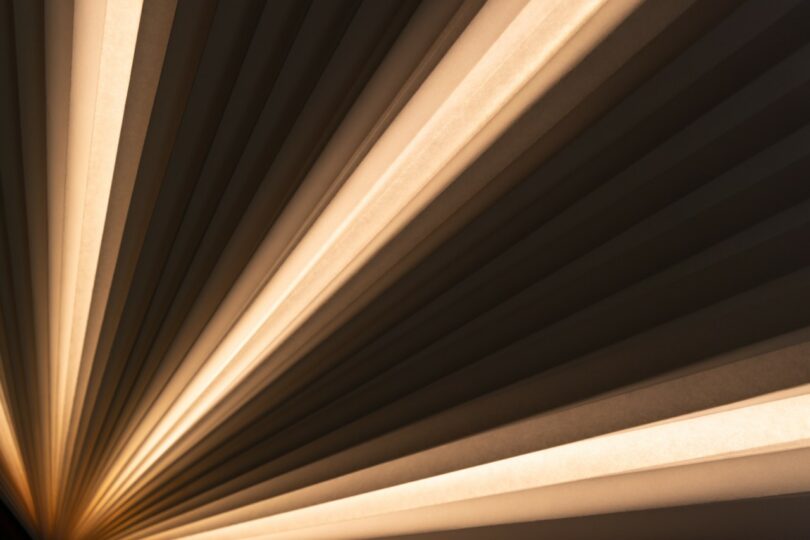 close up of A lamp with a wooden rectangular base and a fan-shaped paper shade 